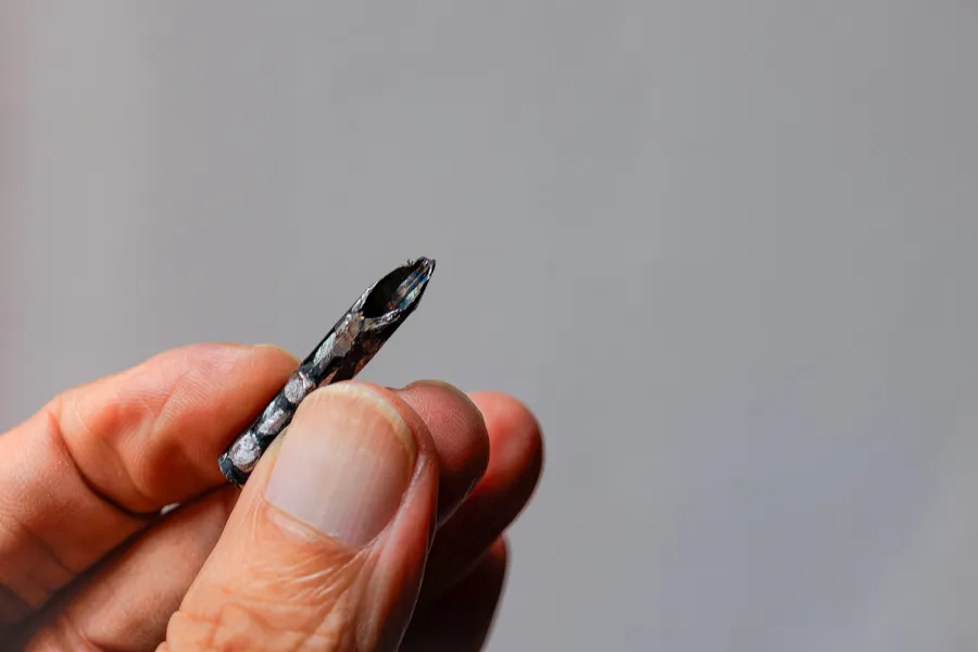 Una mano sosteniendo un pequeño tubo metálico afilado, el dispositivo conocido en Colombia como pito, usado para pinchar llantas