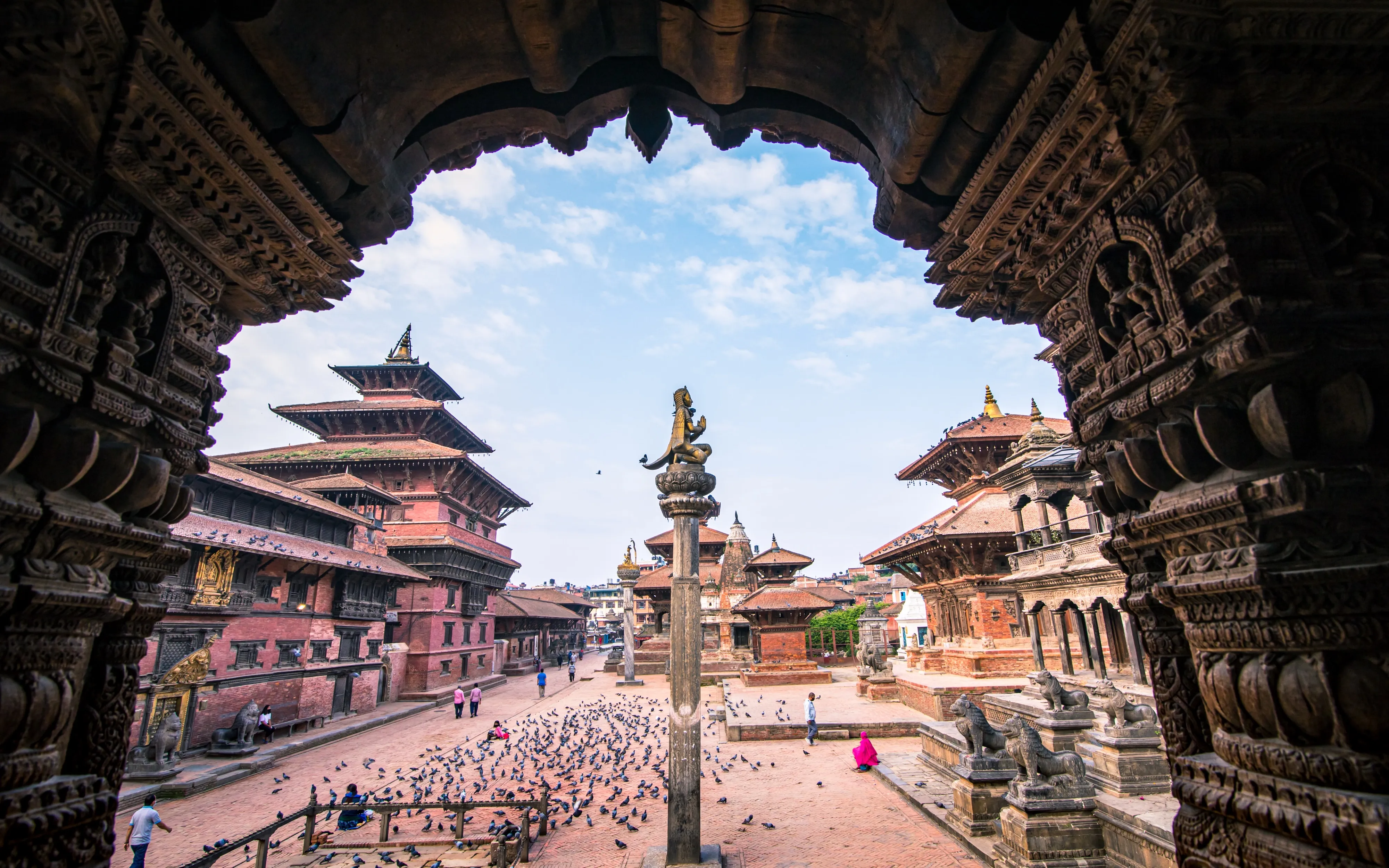 Patan Durbar Square framed by the carved arch of the Krishna Mandir, Nepal