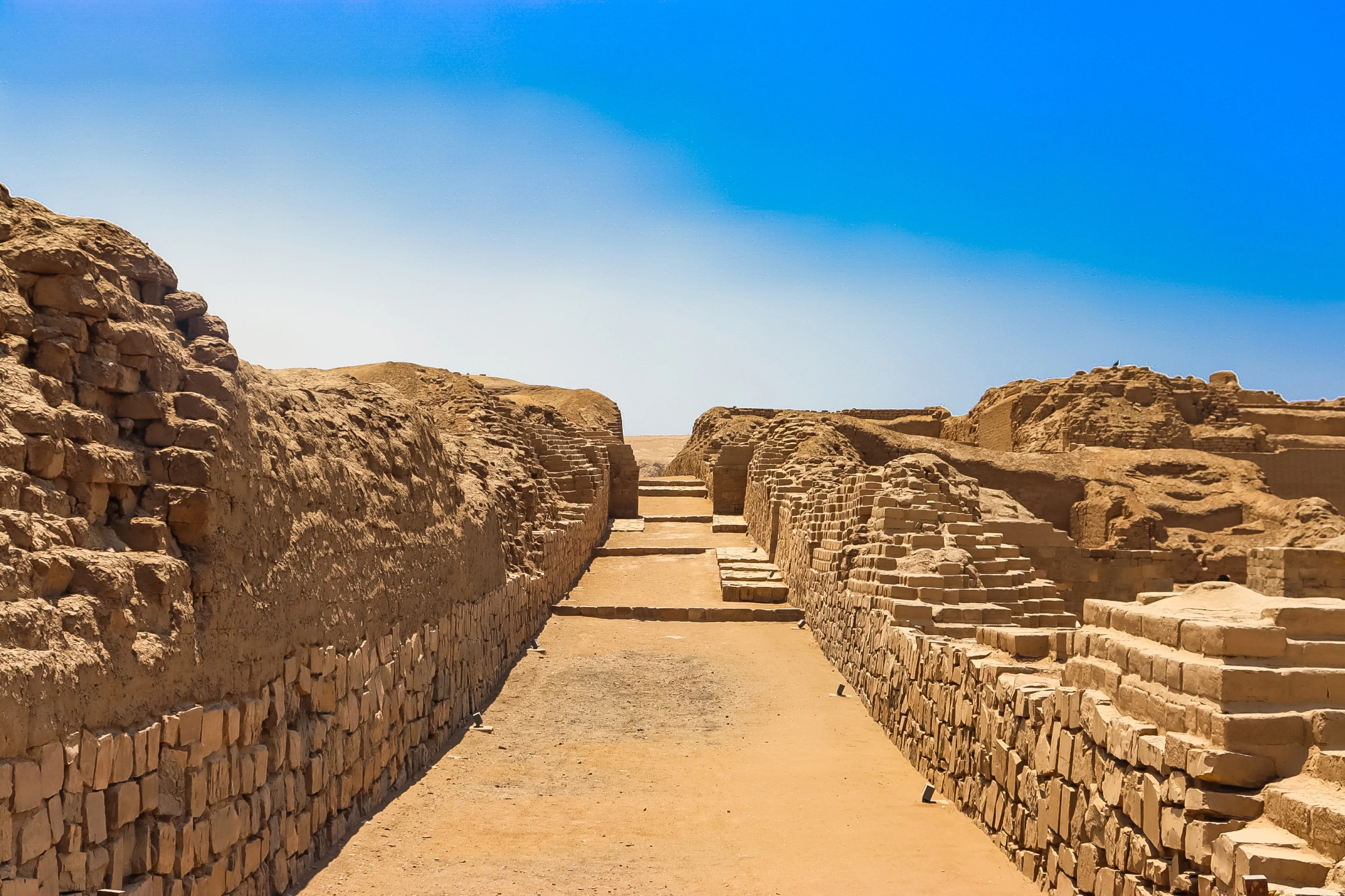 Un pasaje amurallado entre ruinas de adobe en Pachacámac, Perú