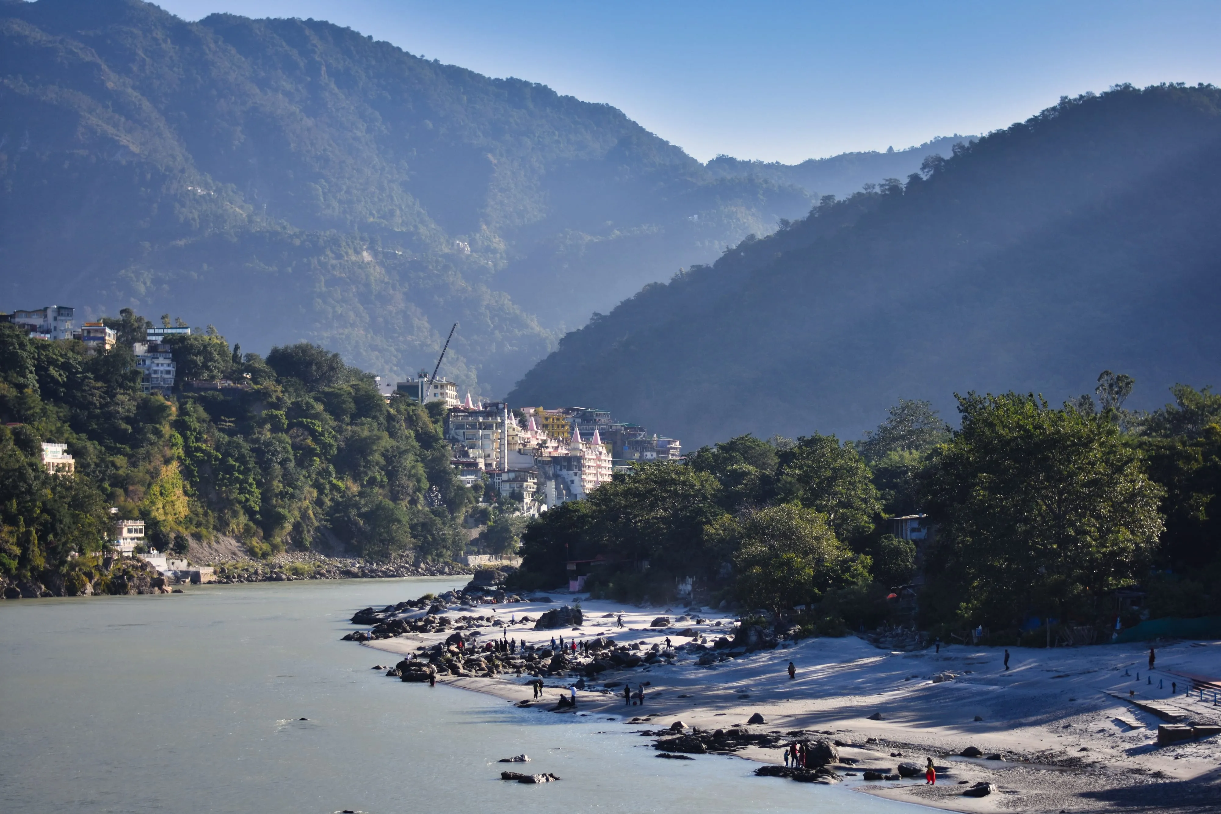 The Ganges flowing past Rishikesh, with forested foothills rising behind the riverside town