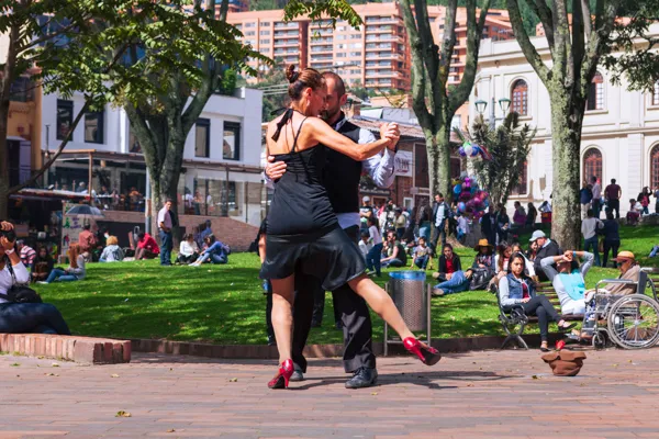 Bailarines de tango actuando en la plaza de Usaquén, Bogotá, con arquitectura colonial al fondo