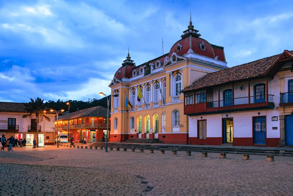 The town hall of Zipaquirá lit up at dusk on the main colonial square, with balconied buildings alongside